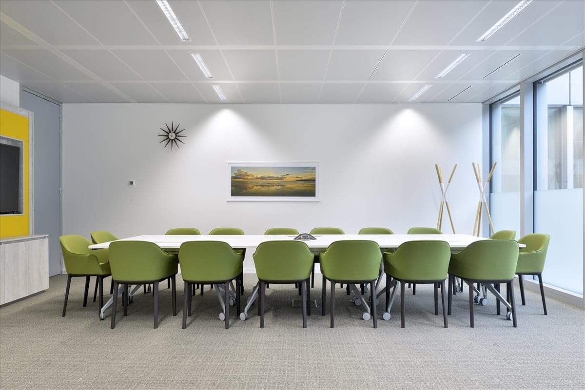 Spacious boardroom at The Voeux with a long white table, green armchairs, and landscape artwork.
