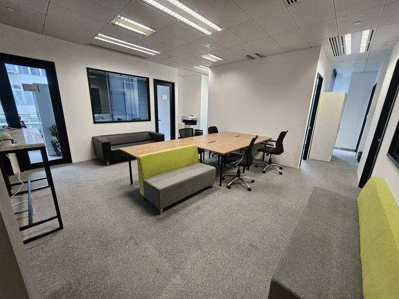 Modern communal workspace at AIA Kowloon Tower featuring a collaborative table and vibrant lime green seating.