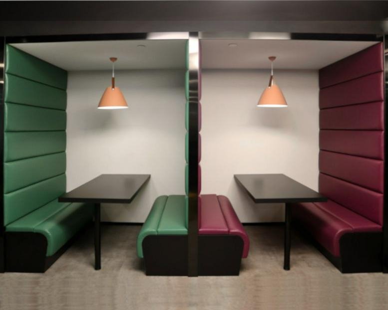 Privacy booths with green and burgundy padded walls and individual pendant lighting.