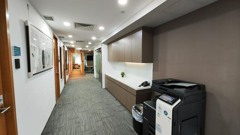 Spacious corridor at Rykadan Capital Tower with wood cabinetry and a printer station.