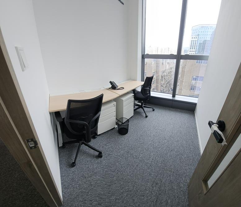 Compact two-person office suite with window view and white storage cabinets.