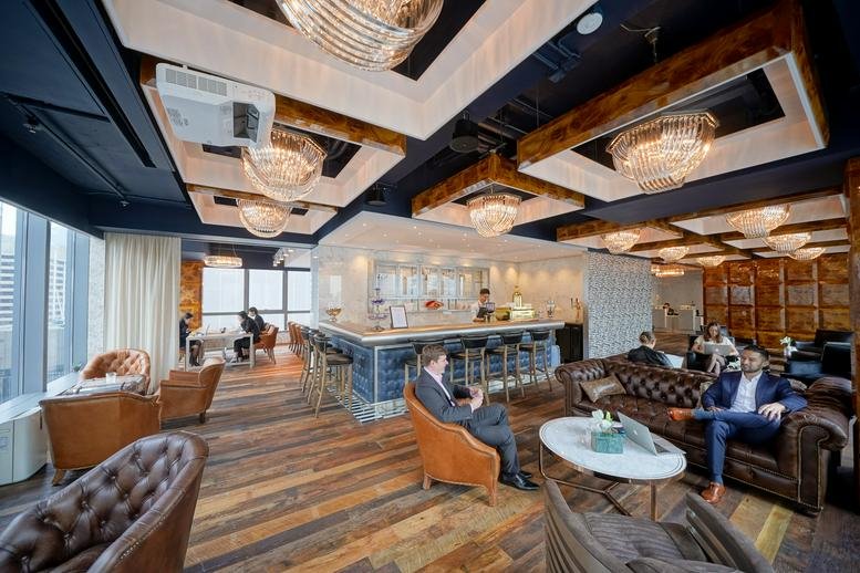 Spacious communal lounge and cafe area with modern lighting and a central bar counter.