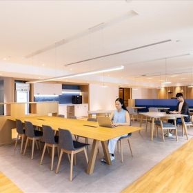 Spacious open-plan coworking area with people working at long wooden tables, Wanchai, Hong Kong. Click for details.